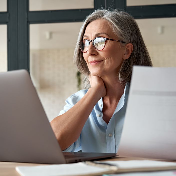 Frau mit grauem Haar vor Laptop beim Online Coaching